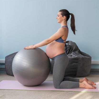femme enceinte a genoux a cote ballon de grossesse
