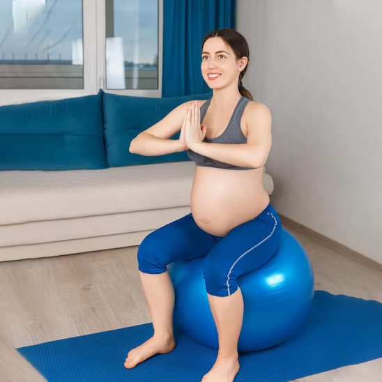 femme enceinte assise sur ballon de grossesse bleu en mode yoga