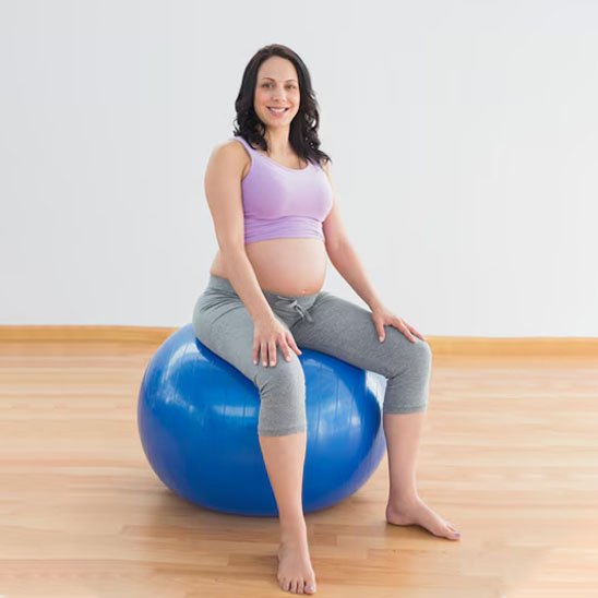 femme enceinte assise sur ballon de grossesse bleu en salle sport