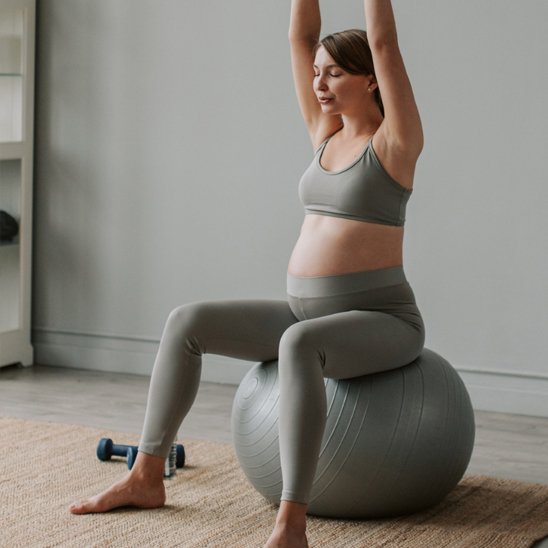 femme enceinte assise sur ballon de grossesse en yoga