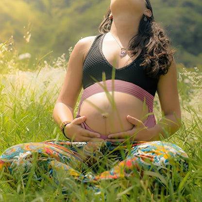femme enceinte dans jardin portant ceinture de grossesse rose
